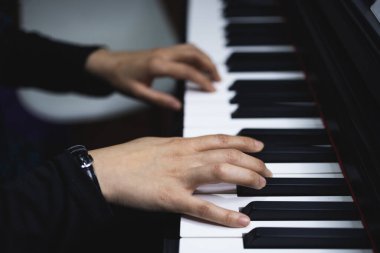 Top view of womans hands playing piano by reading sheet music. High quality photo