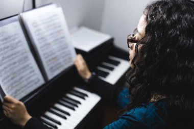 Close up of womans hands playing piano by reading sheet music. High quality photo