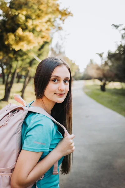 若い学生の女の子は バックパックを運ぶと穏やかな笑顔でカメラを見て 教育の概念 高品質の写真 — ストック写真