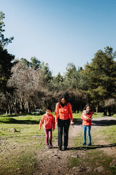 Mother with her two daughters, playing with a golden retriever puppy in the park. Female family. High quality photo