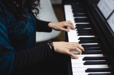 Close up of womans hands playing piano by reading sheet music. High quality photo