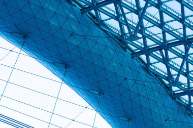 Modern sanayi binasının cam ve çelik inşaatının parlak ve canlı mavi ve yeşil arka planı, süspansiyonlu bina veya köprü, ızgara ve kafes elementleri