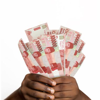 3D 'yi tutan siyah eller 100.000 Endonezya rupiası yaptı. Eller Endonezya para birimini tutarken yakın plan