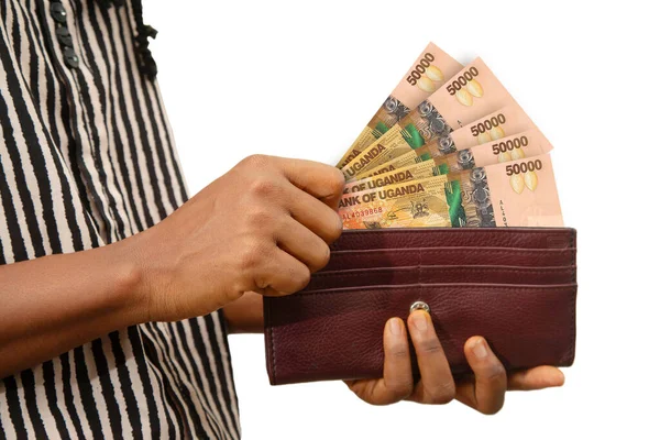 用乌干达先令钞票 手从钱包里掏出钱 孤立在白色上 从皮夹中取出钱 — 图库照片