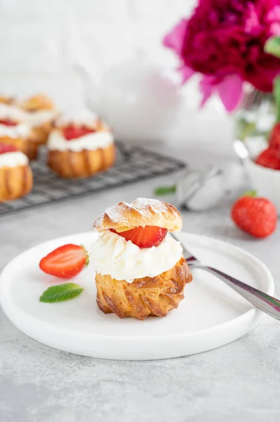 Lezzetli ev yapımı küçük kekler muhallebi, çilek ve gri beton arka planda krema tozlu profiterol choux hamur işi. Boşluğu kopyala