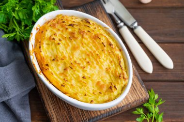 Koyu ahşap arka planda, güveç kabında ev yapımı Shepherd 's Pie. Geleneksel İngiliz yemeği, kıyma ve patates püresi.