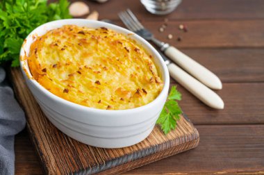 Koyu ahşap arka planda, güveç kabında ev yapımı Shepherd 's Pie. Geleneksel İngiliz yemeği, kıyma ve patates püresi.