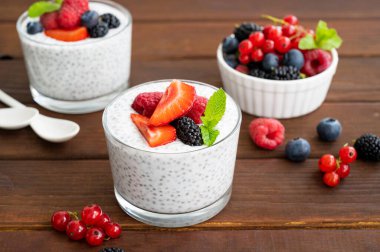 Taze böğürtlenli vanilyalı chia pudingi ve koyu ahşap arka planda bir bardakta bal. Superfood konsepti. Boşluğu kopyala