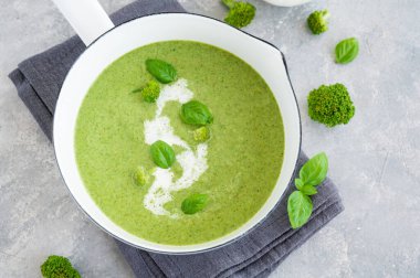 Brokoli kremalı çorba taze fesleğen ve beyaz tencerede kızarmış ekmek ve gri beton arka planda. Boşluğu kopyala