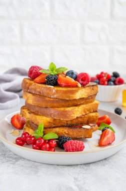 Taze böğürtlen, badem yaprağı ve gri beton arka planda bal dolu bir tabakta bir yığın Fransız tostu. Nefis bir kahvaltı. Boşluğu kopyala