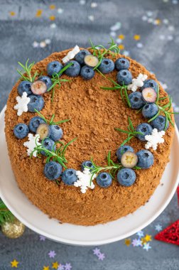 Taze yaban mersinli, biberiyeli ve kar taneli çikolatalı pasta beyaz bir standın üzerinde. Noel ve yeni yıl için pasta. seçici odak.