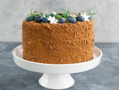 Taze yaban mersinli, biberiyeli ve kar taneli çikolatalı pasta beyaz bir standın üzerinde. Noel ve yeni yıl için pasta. seçici odak.