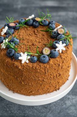 Taze yaban mersinli, biberiyeli ve kar taneli çikolatalı pasta beyaz bir standın üzerinde. Noel ve yeni yıl için pasta. seçici odak.