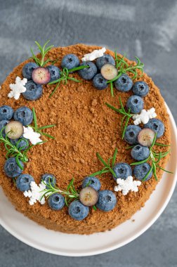 Taze yaban mersinli, biberiyeli ve kar taneli çikolatalı pasta beyaz bir standın üzerinde. Noel ve yeni yıl için pasta. seçici odak.