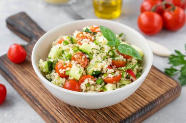 Tabbouleh salatası. Taze sebzeli kuskus salatası ve gri beton arka planda bir kasede taze bitkiler. Boşluğu kopyala