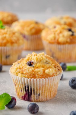 Lemon muffins with blueberries and shtreisel with fresh berries on a gray concrete background. Delicious breakfast. Copy space