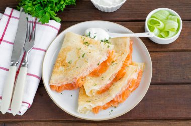 İnce krep ya da füme somon, krem peynir, salatalık ve dereotlu koyu ahşap zemin. Seçici odak