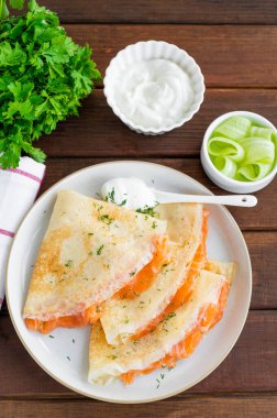 İnce krep ya da füme somon, krem peynir, salatalık ve dereotlu koyu ahşap zemin. Seçici odak