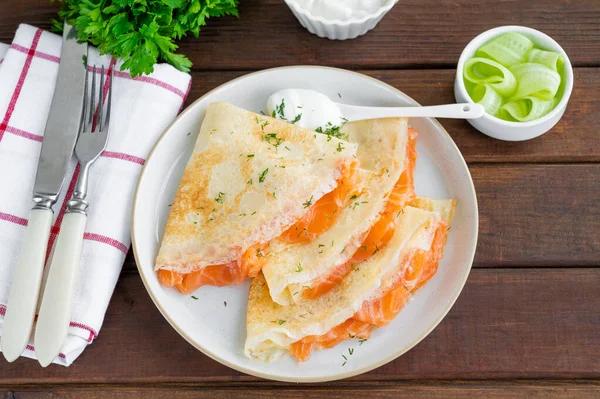 İnce krep ya da füme somon, krem peynir, salatalık ve dereotlu koyu ahşap zemin. Seçici odak