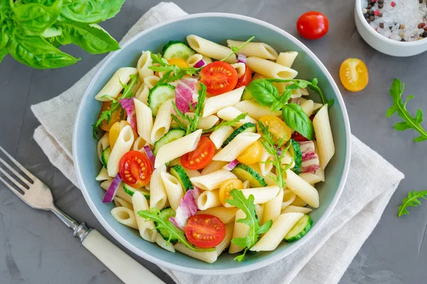 Sağlıklı vejetaryen makarna salatası domatesli, salatalıklı, kırmızı soğanlı ve lahanalı koyu gri arka planda. Boşluğu kopyala