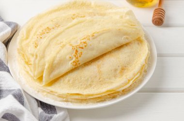 Geleneksel ince krep yığını ya da beyaz ahşap arka planda ballı krep ve ekşi krema. Maslenitsa için yemek. Boşluğu kopyala