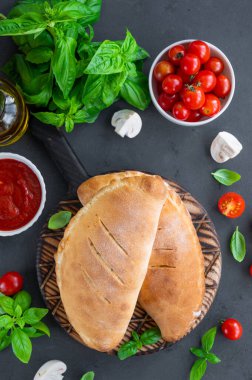 Geleneksel kapalı İtalyan calzone pizzası domates soslu, mozzarella peyniri ve mantarlı koyu arkaplanda. seçici odak, üst görünüm, kopyalama alanı