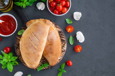 Geleneksel kapalı İtalyan calzone pizzası domates soslu, mozzarella peyniri ve mantarlı koyu arkaplanda. seçici odak, üst görünüm, kopyalama alanı