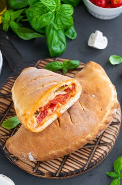 Geleneksel kapalı İtalyan calzone pizzası domates soslu, mozzarella peyniri ve mantarlı koyu arkaplanda. seçici odak, kopyalama alanı