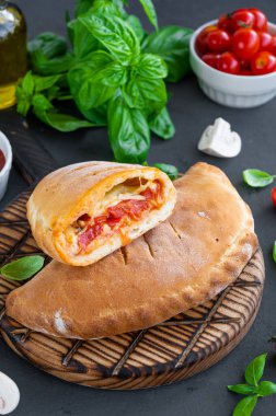 Geleneksel kapalı İtalyan calzone pizzası domates soslu, mozzarella peyniri ve mantarlı koyu arkaplanda. seçici odak, kopyalama alanı