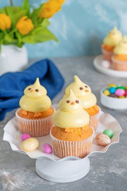 Tatlı Paskalya pilici kekleri. Beyaz bir tezgahta tereyağlı vanilyalı kek ve beyaz ahşap arka planda taze çiçekler. Boşluğu kopyala