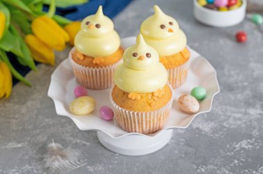 Tatlı Paskalya pilici kekleri. Beyaz bir tezgahta tereyağlı vanilyalı kek ve beyaz ahşap arka planda taze çiçekler. Boşluğu kopyala