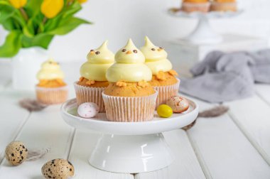 Tatlı Paskalya pilici kekleri. Beyaz bir tezgahta tereyağlı vanilyalı kek ve beyaz ahşap arka planda taze çiçekler. Boşluğu kopyala