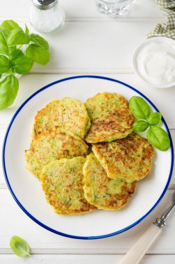 Peynirli, sarımsaklı ve otlu kabaklı börek. Beyaz ahşap arka planda fesleğen ve ekşi kremayla servis edilen vejetaryen kabaklı gözleme. Seçici odak