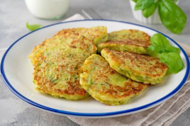 Peynirli, sarımsaklı ve otlu kabaklı börek. Vejetaryen kabaklı gözleme, gri beton arka planda fesleğen ve ekşi kremayla servis ediliyor. Seçici odak