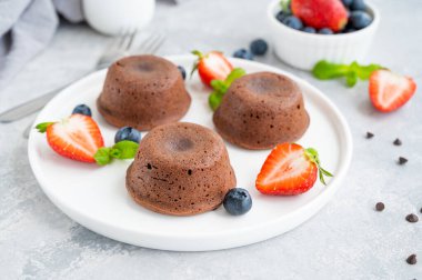 Gri arkaplanda taze böğürtlenli çikolatalı lav keki.