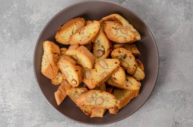 Geleneksel İtalyan cantuccini kurabiyeleri ve gri beton arka planda bir tabakta badem. Üst görünüm