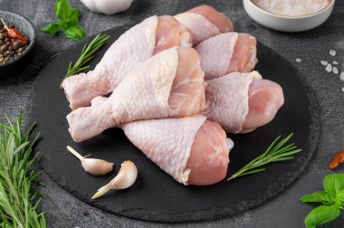 Koyu beton bir zeminde çiğ tavuk budu. Pişirmek için malzemeli et. Üst görünüm