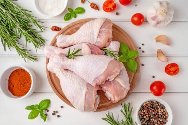 Çiğ tavuk budu beyaz ahşap bir arka planda kesim tahtasının üzerinde. Yemek yapmak için malzemeli et..