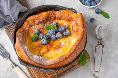 Taze yaban mersinli ev yapımı Hollanda usulü krep, nane şekeri ve gri beton arka planda demir tavalarda krema serpiştirilmiş. Boşluğu kopyala