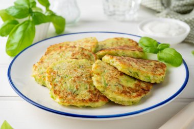 Peynirli, sarımsaklı ve otlu kabaklı börek. Beyaz ahşap arka planda fesleğen ve ekşi kremayla servis edilen vejetaryen kabaklı gözleme. Seçici odak