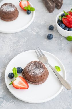 Gri arkaplanda taze böğürtlenli çikolatalı lav keki.