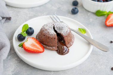 Gri arkaplanda taze böğürtlenli çikolatalı lav keki.