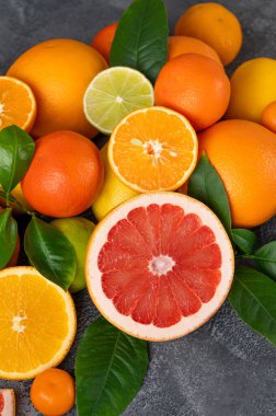 Beton arka planda yaprakları olan farklı narenciye meyveleri. Sağlıklı yiyecekler. Üst görünüm.