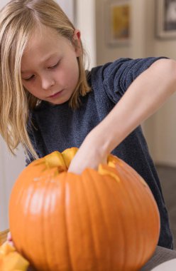 Balkabağı oyan ve ellerini kirleten mutlu sarışın çocuk. Kirli ellere odaklan. Cadılar Bayramı konsepti