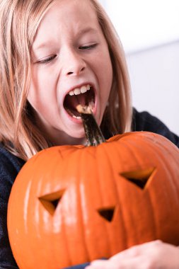 Balkabağı oyan ve ellerini kirleten mutlu sarışın çocuk. Kirli ellere odaklan. Cadılar Bayramı konsepti