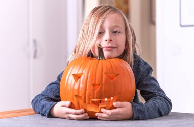 Balkabağı oyan ve ellerini kirleten mutlu sarışın çocuk. Kirli ellere odaklan. Cadılar Bayramı konsepti