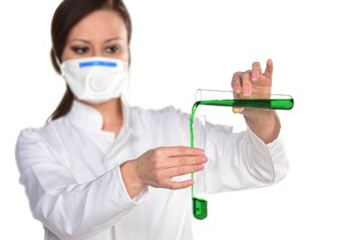 Koruyucu maskeli genç bir kadın ve beyaz üzerinde sıvı bulunan test tüpü.