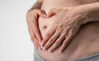 partial view of pregnant woman, hands on belly 