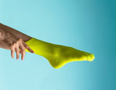 cropped image, woman adjusting  bright green sock on foot 