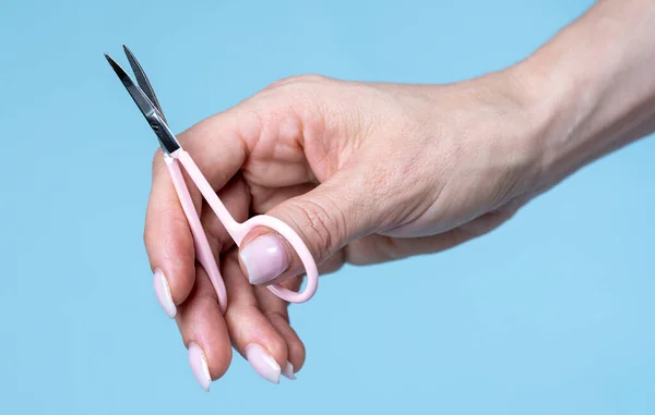 Female Hand Holding Manicure Scissors Blue Background — Fotografia de Stock